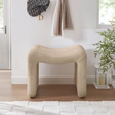 a white bench sitting in front of a window next to a potted plant and coat rack