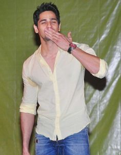 a man standing in front of a green backdrop holding his hands to his mouth and making a funny face