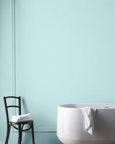 a chair sitting next to a bath tub in a room with blue walls and flooring