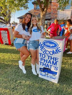 two girls posing in front of a welcome to the ham that's sign at a car show