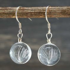 "Artistic and fun, the Wish Earrings have quickly become a natural classic. This lovely pair of earrings was inspired by the dandelions which grace the rolling hills of Chadds Ford, Pennsylvania. \"Nature is loved by what is best in us.\" --Ralph Waldo Emerson Details: Crystal Dandelion Seed Pendants Solid Sterling Silver Hooks, Nickel-Free & Hypoallergenic Seed Pendant Size: 11mm (Diameter) Our Collections: We invite you to indulge in the exquisite allure of our handcrafted country- and nature-themed jewelry collections. From keepsake earrings and necklaces to bracelets and rings, each piece emanates a timeless beauty and undeniable charm. Whether you find solace in the serenity of nature or simply appreciate the rustic elegance that it embodies, our jewelry is sure to leave a lasting imp Nature-inspired Dangle Hoop Earrings For Gift, White Hypoallergenic Nature-inspired Earrings, Hypoallergenic White Nature-inspired Earrings, Nature-inspired Hypoallergenic White Earrings, Hypoallergenic Nature-inspired Round Earrings, Silver Nature-inspired Jewelry With Pressed Flowers, Silver Pressed Flowers Drop Earrings, Dandelion Earrings, Nature-inspired Dangle Earrings With Pressed Flowers