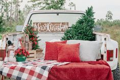 an old truck is decorated for christmas with red and white plaid throw pillows on the bed