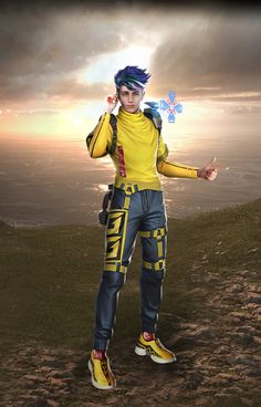 a man standing on top of a hill wearing yellow and blue clothing with his hands in the air