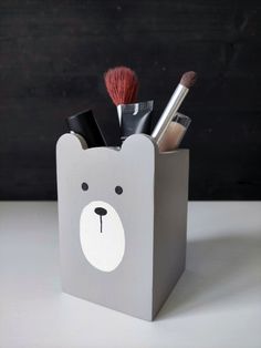 a gray bear shaped container with makeup and brushes in it