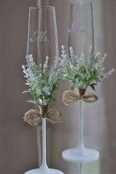 two wine glasses decorated with flowers and twine