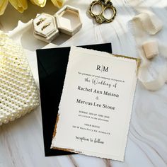 a black and white wedding card with gold foil on it, surrounded by other items