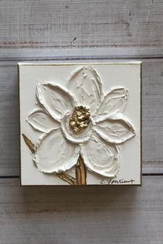 a white and gold painted flower on a wooden surface