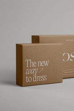 two cardboard boxes with the words, the new way to dress printed on them are sitting side by side