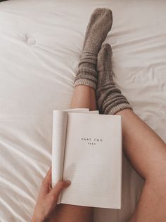 a person laying in bed with their legs crossed and reading a book that reads pretty pom pom