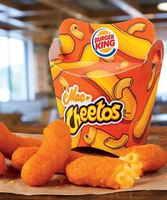 a box of cheetos sitting on top of a table next to some fried food