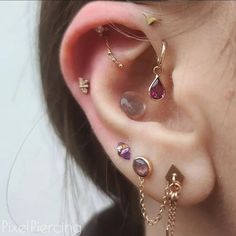 a woman wearing ear piercings with different colored stones