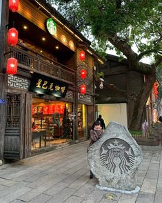 a person sitting on a rock in front of a building