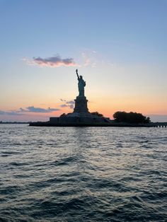 the statue of liberty is silhouetted against an orange and blue sky as it stands in the water