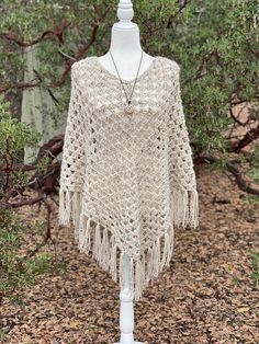 a crocheted shawl on a mannequin with trees in the background