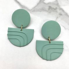 a pair of green earrings on a marble surface