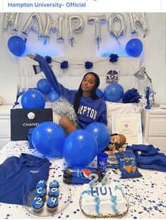 a woman sitting on top of a bed surrounded by blue balloons and other items in front of her