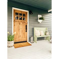 a wooden door sitting on the side of a house next to a bench and potted plant