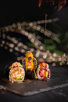 sushi rolls are being served on a plate with someone pouring sauce over them to make it look like they have been made out of rice