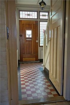 an open door leading to another room with a checkered floor and large wooden door