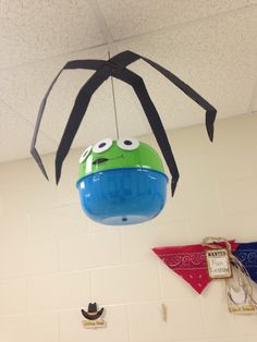 a green and black spider hanging from the ceiling in a room with other decorations on the wall