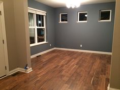 an empty room with hard wood flooring and blue walls, white trim on the windows