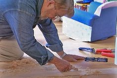 an older man laying on the floor with tools in front of him and looking at something