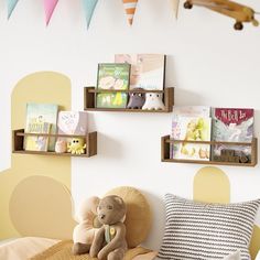 a teddy bear sitting on top of a bed next to two bookshelves filled with children's books