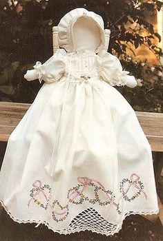 a white dress and bonnet sitting on top of a wooden bench