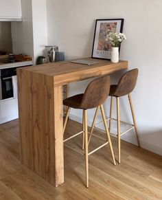 two wooden stools sit at the counter in this modern kitchen with white walls and wood flooring