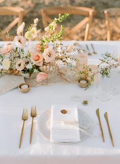 the table is set with flowers and goldware