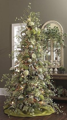 a decorated christmas tree in the corner of a room with a mirror on the wall