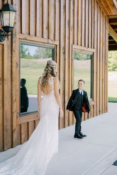 the bride and groom are standing in front of the barn door looking at each other