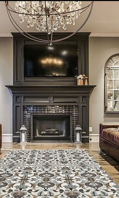 a living room with couches and a fireplace in the center, chandelier hanging from the ceiling