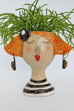 a ceramic vase with a plant in it's head