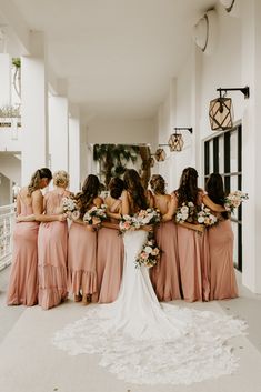 a group of bridesmaids in pink dresses standing around each other with their backs to the camera