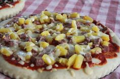 an uncooked pizza sitting on top of a red and white checkered table cloth