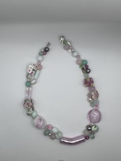 Pulling from the delicate and sweet color pallet of a petit four, this necklace features light green, baby pink, and white beads. The beads are of various shades, transparencies, shapes, and sizes. There are glass beads, freshwater water pearls, jade beads. They are beautifully suspended on three strands of silver-toned wire. The necklace is 14 inches long with a toggle clasp. Pink Glass Necklace With Round Beads, Pastel Beaded Necklaces With Round Beads, Pink Single Strand Glass Necklace, Cute Pink Necklaces With Tiny Beads, Pink Beaded Glass Necklaces, Pink Glass Beaded Necklaces, Whimsical Pink Beaded Necklaces With Round Beads, Pink Glass Necklace With Colorful Beads, Whimsical Pink Beaded Necklaces