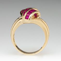 a yellow gold ring with pink and white stones in the center, on a gray background