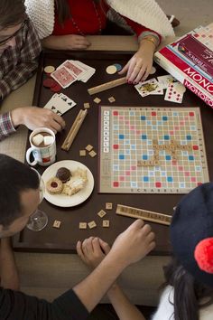 three people sitting at a table playing a board game