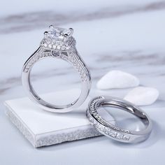 two wedding rings sitting on top of a white marble block with the words jeula written below them