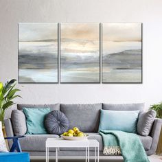 three paintings on the wall above a couch in a room with blue and white furniture