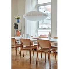 a dining room table with four chairs and a white light hanging from the ceiling over it