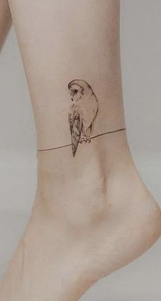 a small tattoo on the ankle of a woman with an owl sitting on a wire