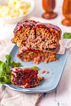 a piece of meatloaf is being lifted from a blue plate with sauce on it