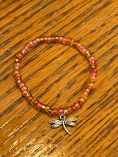 Dragonfly charm bracelet with sunset colored glass beads. It has orange, pink and yellow and looks beautiful in the sun. The seed beads make it appear delicate and dainty. The charms come from a local, independent store near me. Buying this bracelet helps me support my local community. If I am able to sell these, I will buy more. All the charms there are responsibly sourced. It is perfect for girls as a gift for your daughter, granddaughter, niece, sister, friend or more. It is also a great gift for woman especially if they love nature and animals like me. It will come before Christmas as a perfect gift to get part of your shopping completed Adjustable Orange Beaded Bracelet With Lobster Clasp, Orange Beaded Bracelet With Lobster Clasp As Gift, Adjustable Nickel-free Orange Bracelets, Adjustable Nickel-free Orange Bracelet, Cat Charm Bracelet, Dragonfly Charm, Moms Bracelet, Great Gifts For Women, Christmas Bracelet