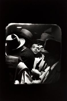 black and white photograph of two men sitting in a car with hats on their heads