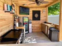 the inside of a small cabin with wood paneling and ceiling fan, stove, refrigerator, cabinets, and counter tops