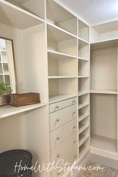 an empty walk in closet with white shelves and drawers