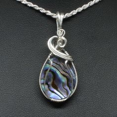 "Wire Wrap Jewelry Description:  *Designer Cabochon Gemstone: Abalone (25mm x 20mm Teardrop Shaped) *Approximate size:  2\" long including bail x 3/4\" at widest point *Includes Free Rope Chain *Free Domestic Shipping - Arrives in Gift Box - Gift Wrapping Available  The contemporary wire wrap jewelry is hand wire sculptured using sterling silver wire around the natural cabochon gemstone to form this simple delicate handmade wire wrap pendant statement necklace. The bail is large enough to accommodate various style chains. Each wire wrap pendant is handmade by me from inception to finished product. They are not mass produced nor manufactured; each unique piece is one of a kind. This is the exact pendant you will receive when purchased. We welcome general inquiries - Just Ask your questions. Abalone Jewelry, Bijoux Fil Aluminium, Wire Wrap Jewelry, Gemstone Pendants, Wrap Jewelry, Sterling Silver Wire Wrap, Handmade Wire Wrapped, Handmade Wire, Box Gift