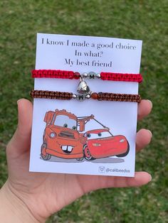 a hand holding up a card with a car charm on it and a red cord